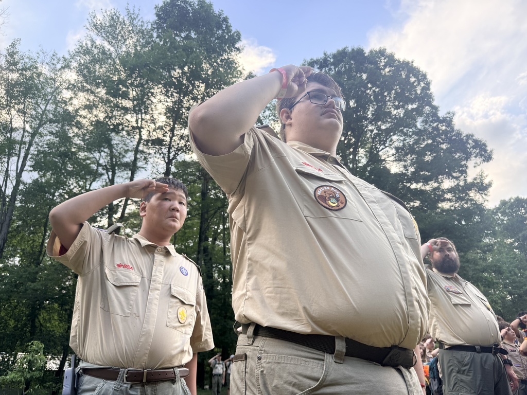 Tristian and Carson dressed in tan-colored Scouting uniforms stand tall as they salute.