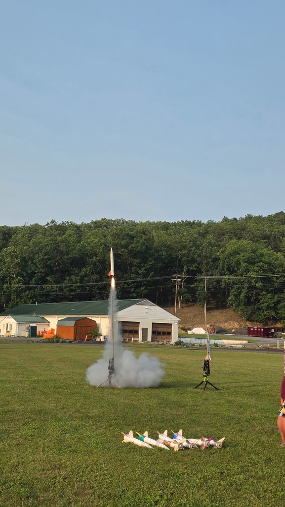 A white rocket with a red tail begins to launch off the launchpad. There is smoke coming from the bottom of the rocket.