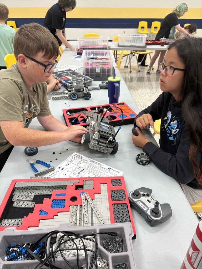 Camp participants sitting across from one another work together to build a VEX robot.