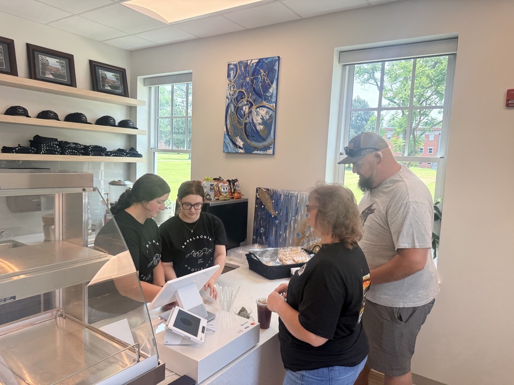 Two customers place an order at the counter while student employees assist them inside Appalachia Provisions Café during a Deaf Chat community gathering.