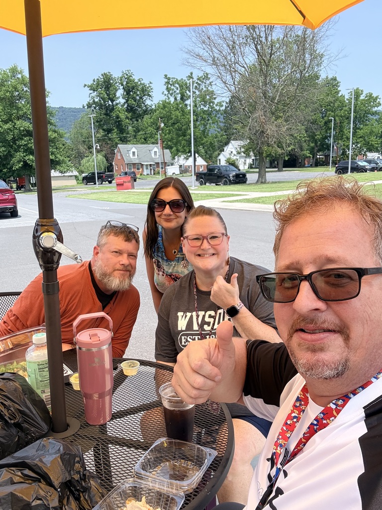 Attendees enjoy lunch and conversation around an outdoor patio table with umbrellas during a Deaf Chat gathering at Appalachia Provisions Café.