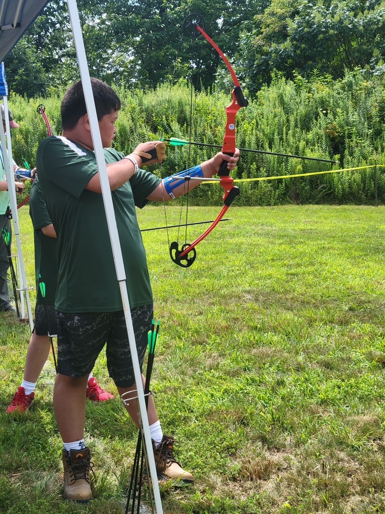 A Scout draws a recurve bow and aims toward the target during supervised archery practice at the National Jamboree.
