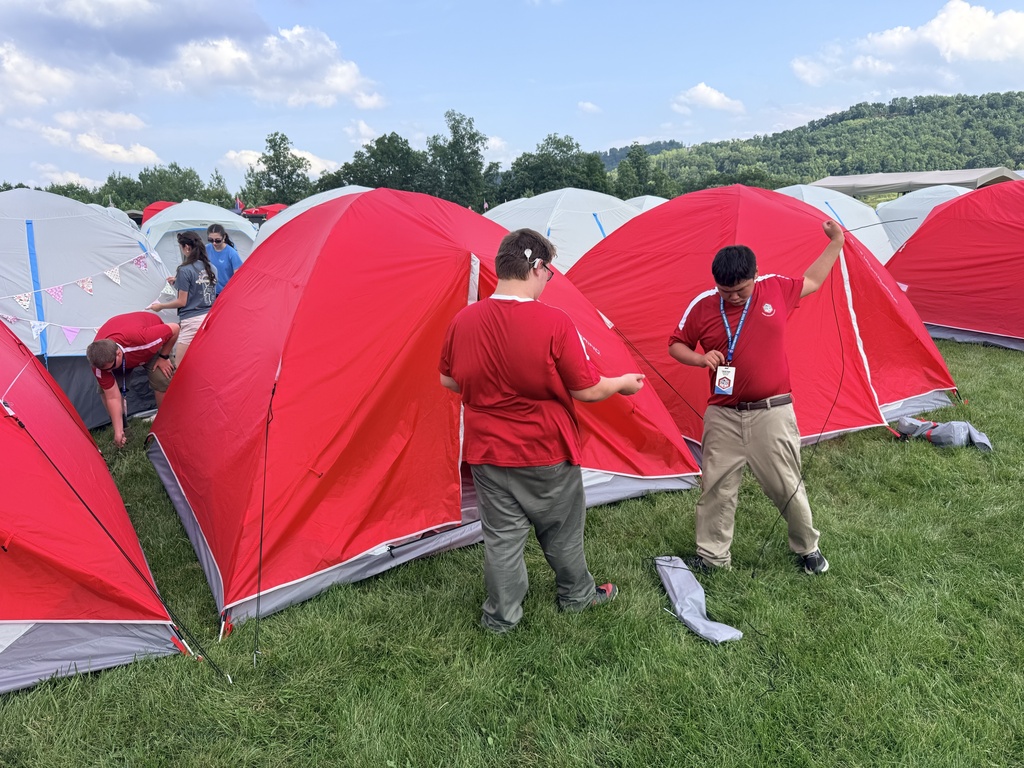 Scouts work together to assemble bright red tents in their campsite on the first day of the National Jamboree.