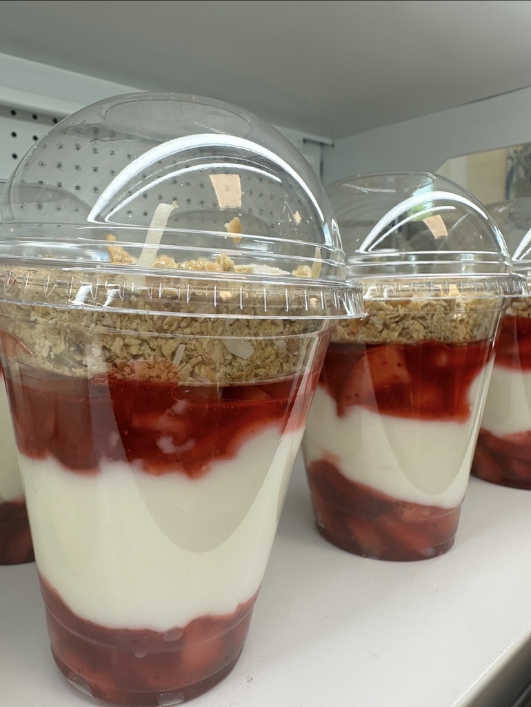 Strawberry pecan yogurt parfait layered with creamy yogurt, fresh strawberries, and crunchy granola in a clear to-go cup.