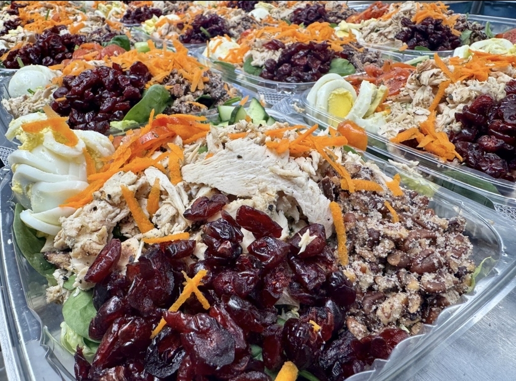 Fresh cranberry pecan chicken salad with grilled chicken, spinach, dried cranberries, shredded carrots, hard-boiled egg, cucumbers, and candied pecan.