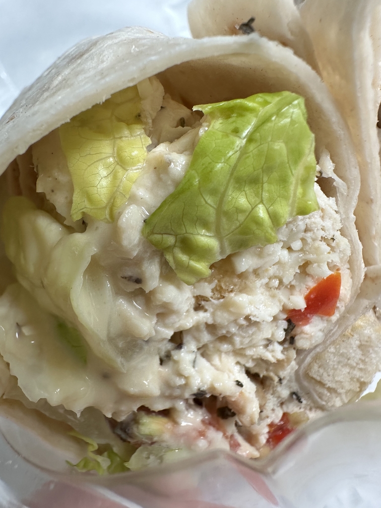 Close-up of a grilled chicken Caesar wrap filled with seasoned chicken, crisp romaine lettuce, creamy Caesar dressing, and Parmesan cheese.