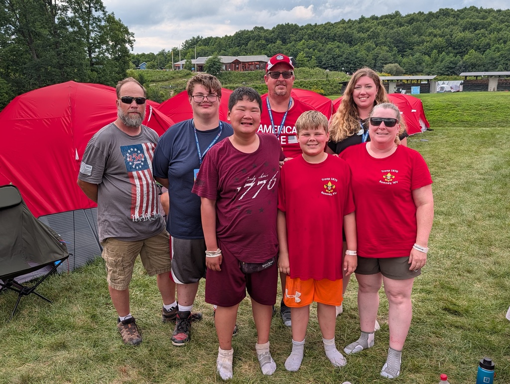 WVSDB Boy Scouts, WVSDB staff members, and troop leaders stand together in front of their campsite tents during the National Scout Jamboree.
