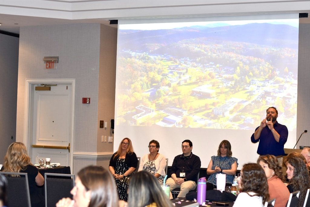 An interpreter signs at the front of the conference room during a presentation at the 2026 WVSDB Interpreter Summit.