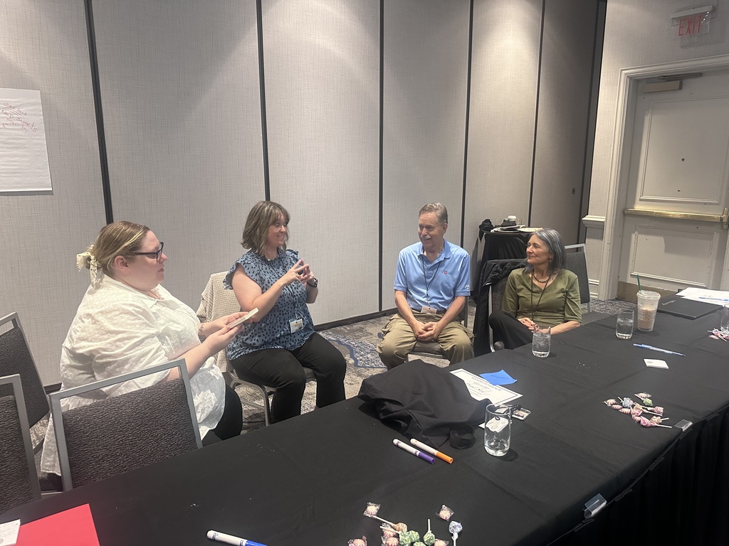 Four Interpreter Summit participants sit together around a table during a small-group discussion and activity.