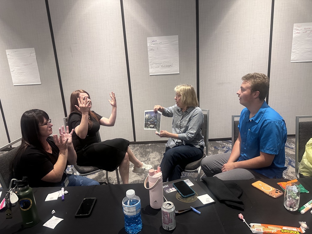 Four participants engage in an interactive small-group activity during the 2026 WVSDB Interpreter Summit, with several participants using sign language.
