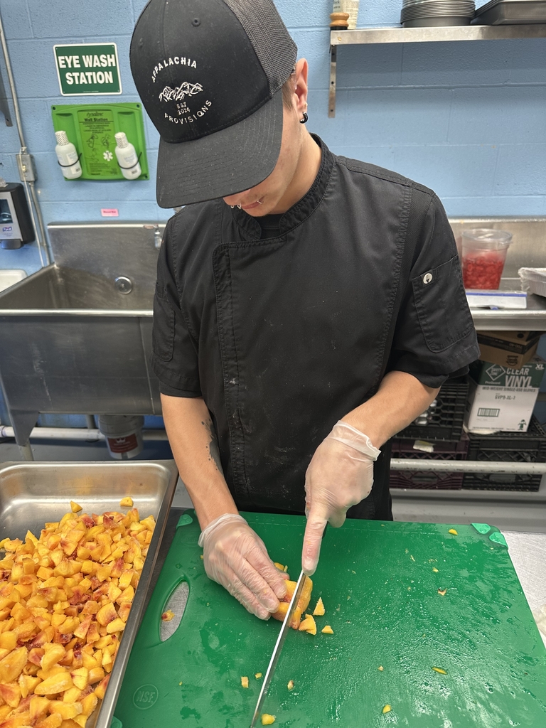 Appalachia Provisions student dices fresh peaches on a cutting board while preparing café menu items.