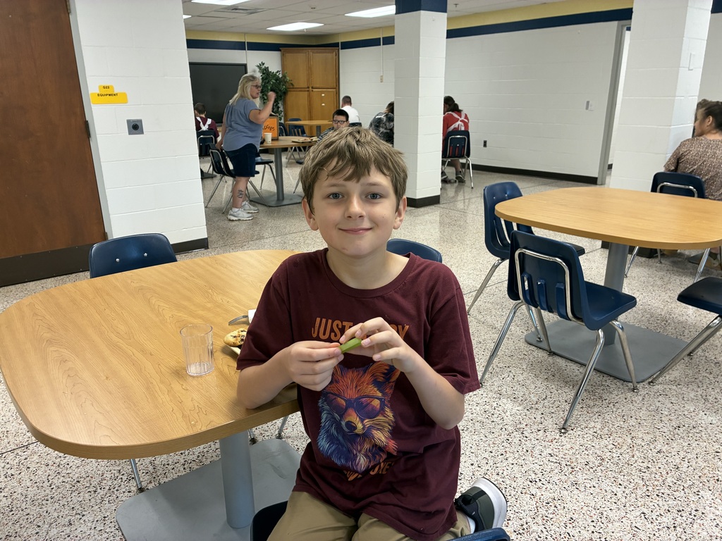 A WVSDB student smiles at the camera while seated at a cafeteria table during the UAW Local #1590 annual picnic.