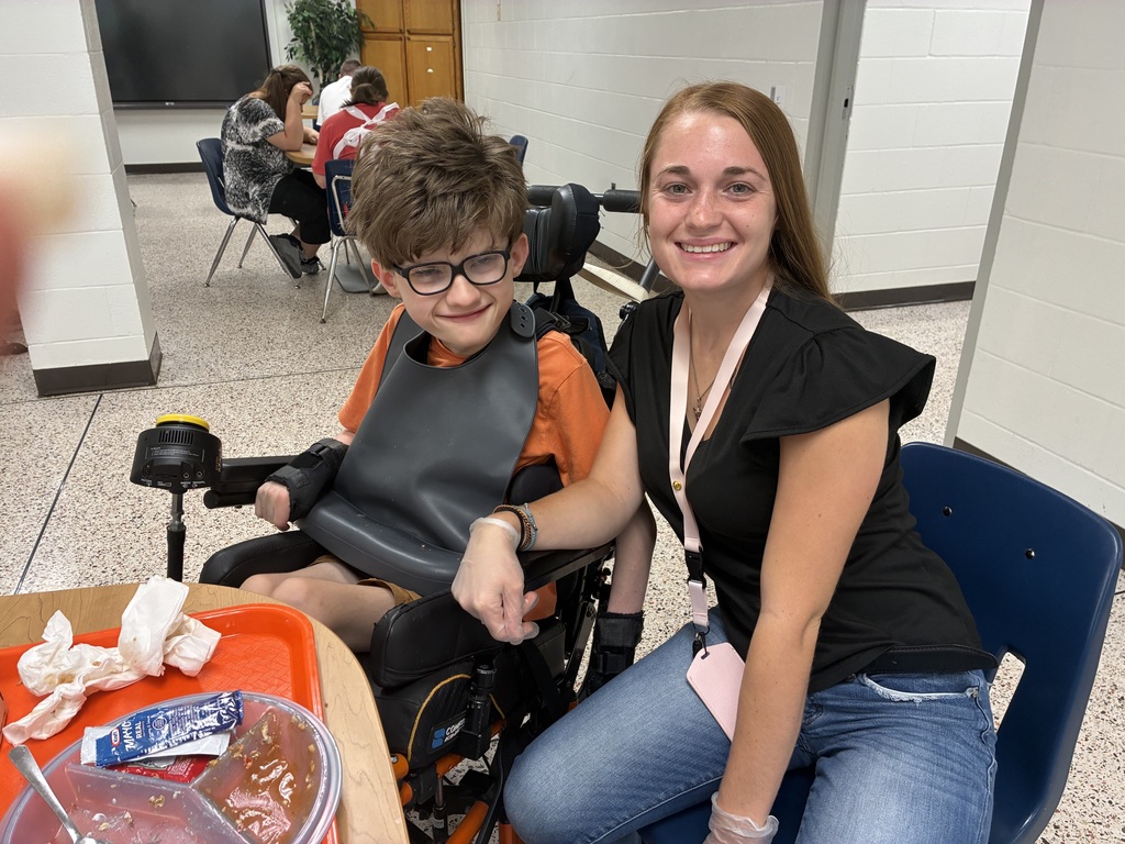 A WVSDB student using a wheelchair smiles alongside a staff member during the UAW Local #1590 annual picnic.