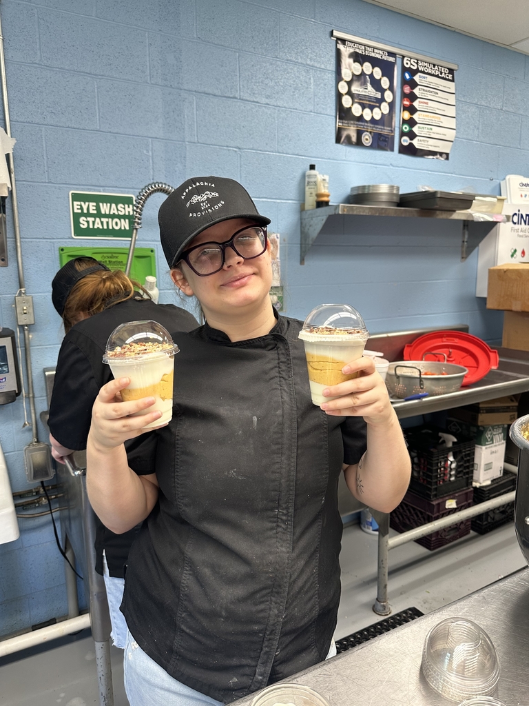 WVSDB Appalachia Provisions culinary student wearing a black chef coat and branded cap holds two freshly prepared pumpkin pecan yogurt parfaits in the café kitchen.