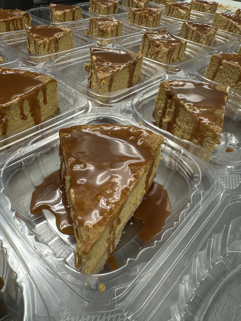 Close-up of individual slices of caramel pumpkin cheesecake in takeout containers, generously drizzled with caramel sauce and ready to serve.