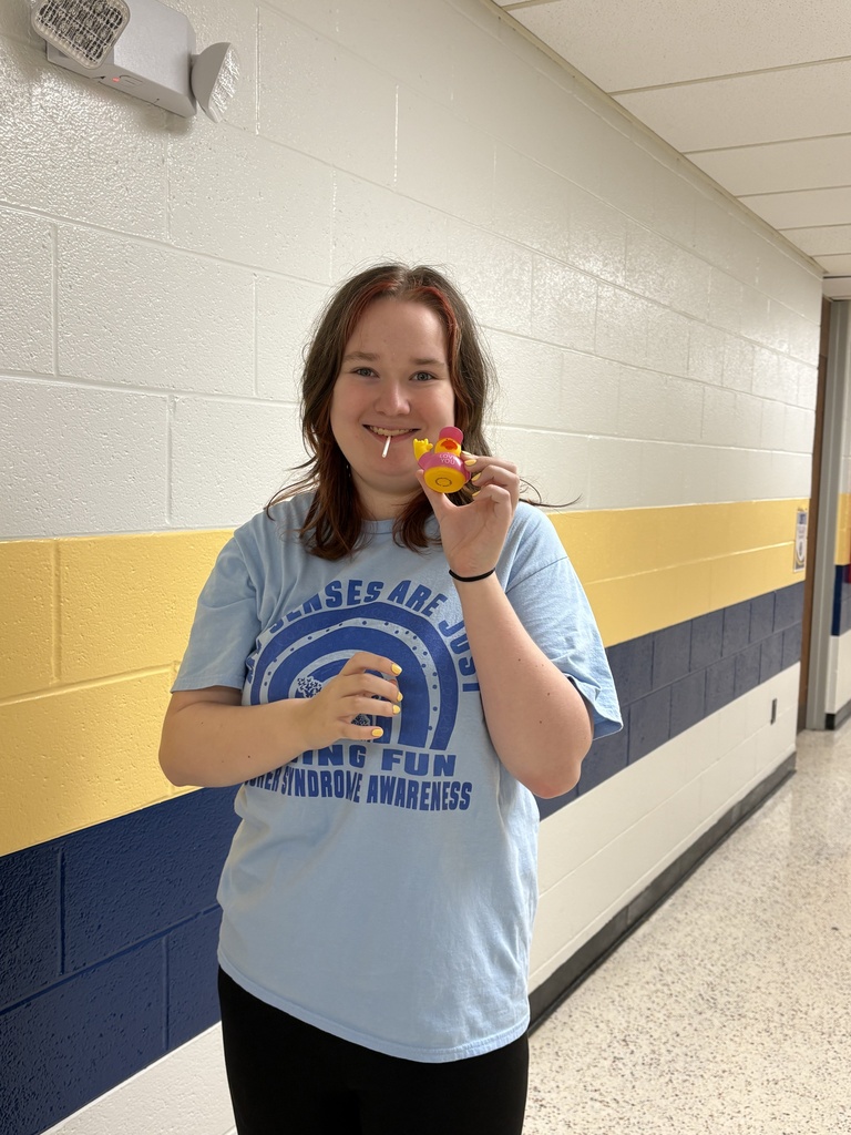 A smiling student holds up the “I Love You” duck she discovered in a school hallway.