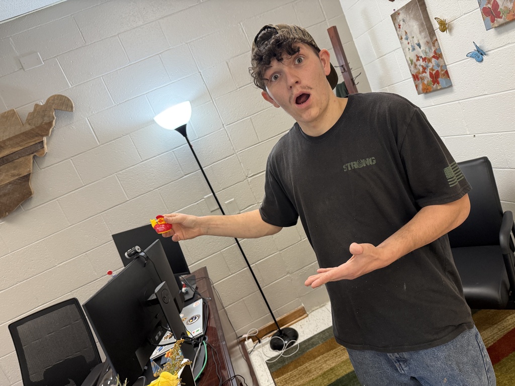 A student reacts with surprise while holding an “I Love You” duck he discovered near a computer workstation.