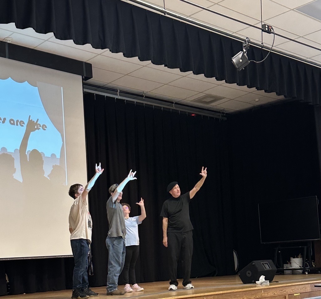 JJ Jones and three WVSDB participants stand on stage with their hands raised during an interactive portion of the performance.