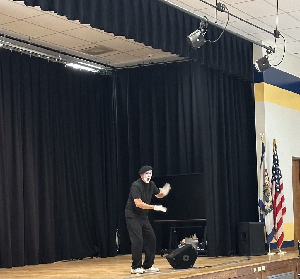 Deaf Mime JJ Jones performs alone on the WVSDB stage, dressed in black with traditional white mime makeup and gloves.