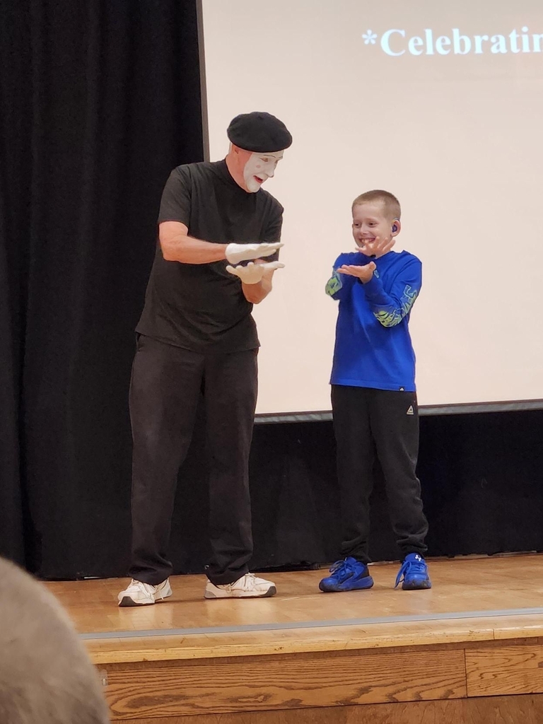 Deaf Mime JJ Jones and a smiling WVSDB student participate together in an interactive mime activity on stage.
