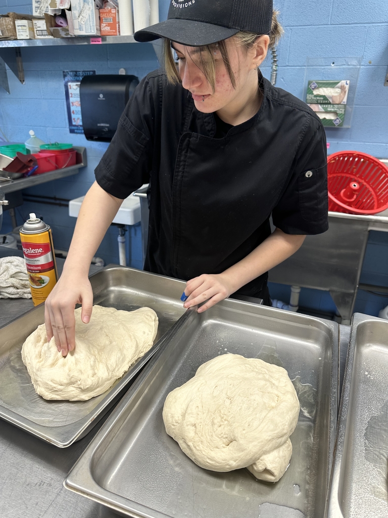 An Appalachia Provisions culinary student shapes fresh dough on baking sheets in the kitchen.