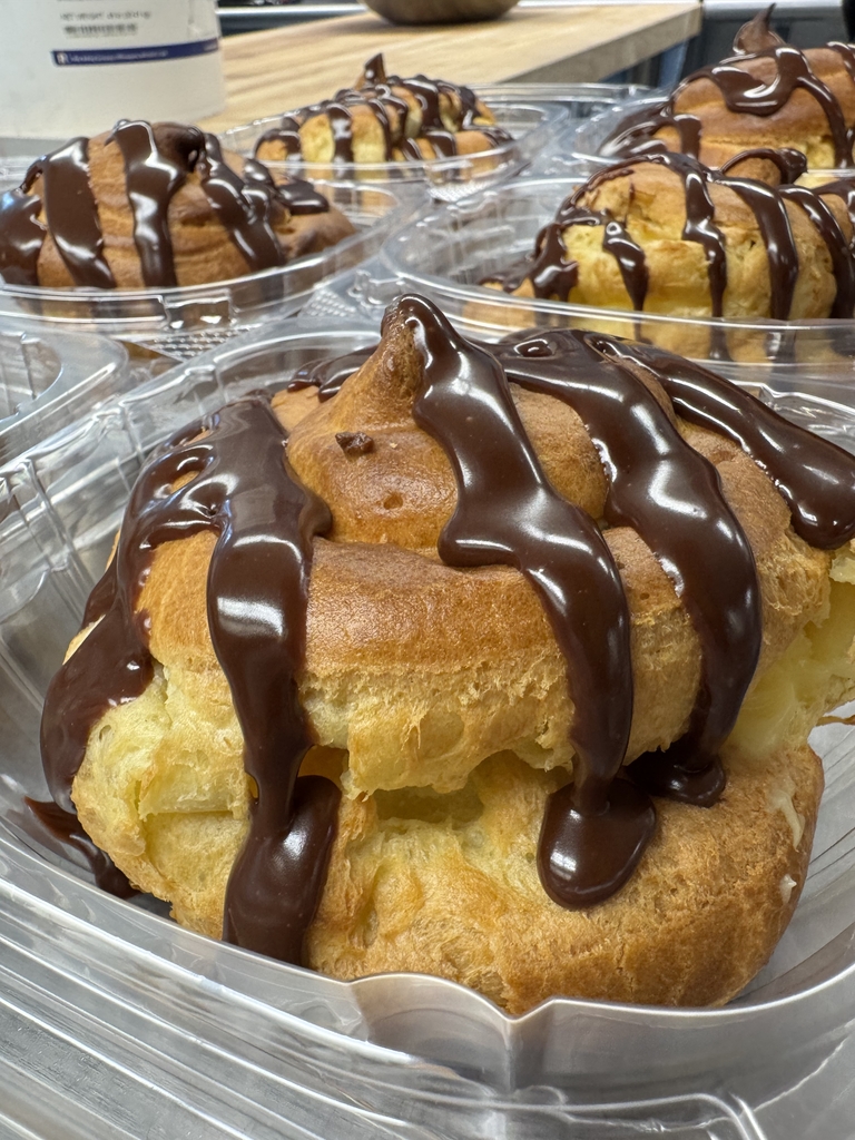 Large cream-filled pastries topped with chocolate drizzle, packaged and ready to serve at Appalachia Provisions.