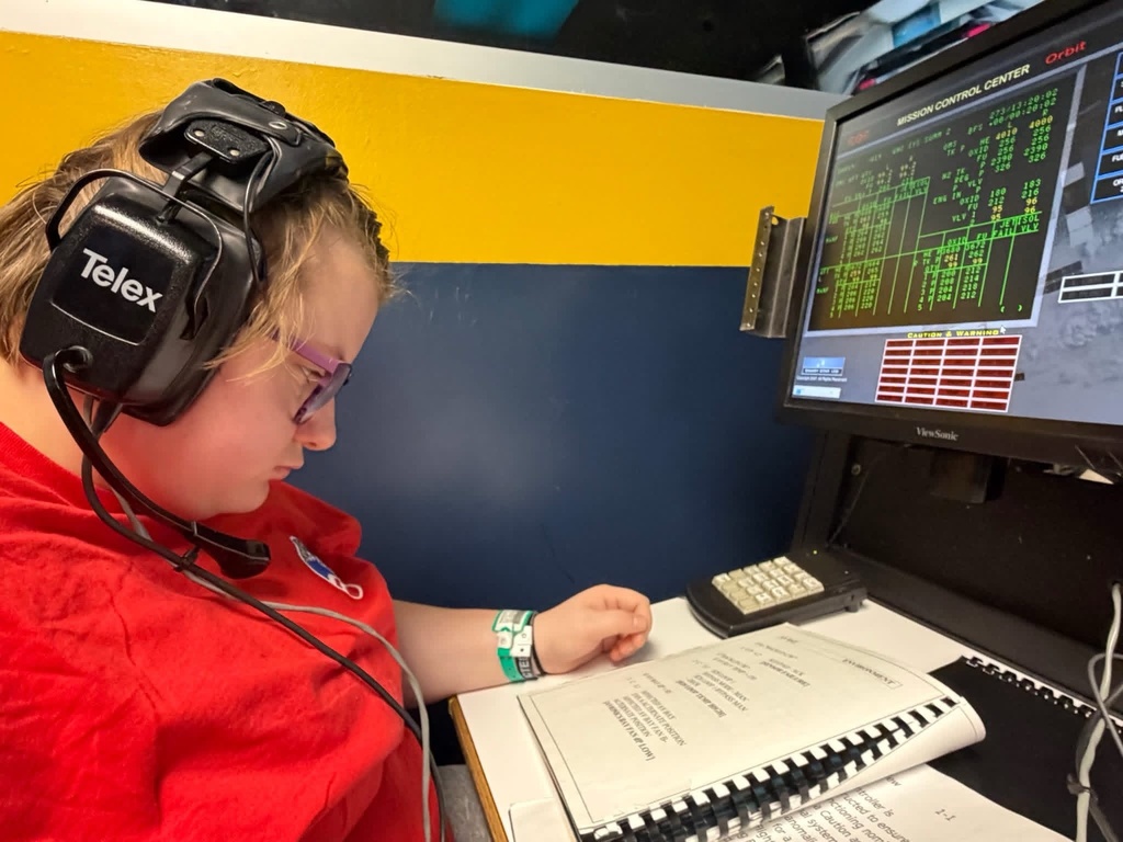 A WVSDB student wearing a headset works at a mission control station during a hands-on Space Camp simulation.