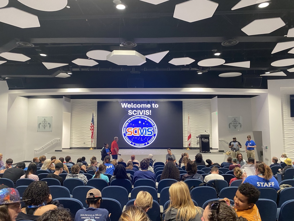 Students and staff gather in an auditorium for SCIVIS, Space Camp for Interested Visually Impaired Students. A large screen at the front displays the SCIVIS welcome logo.