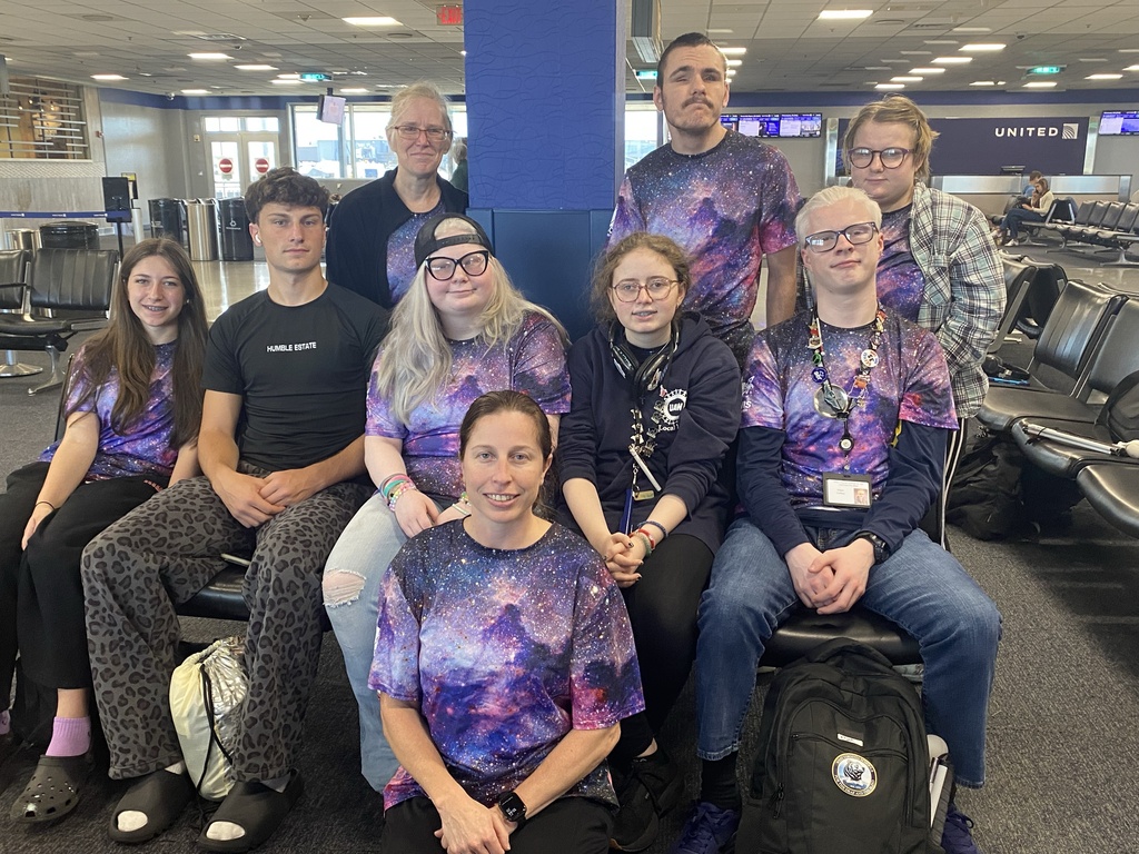 WVSDB students and staff wearing galaxy-themed shirts pose together at the airport during their SCIVIS Space Camp trip.