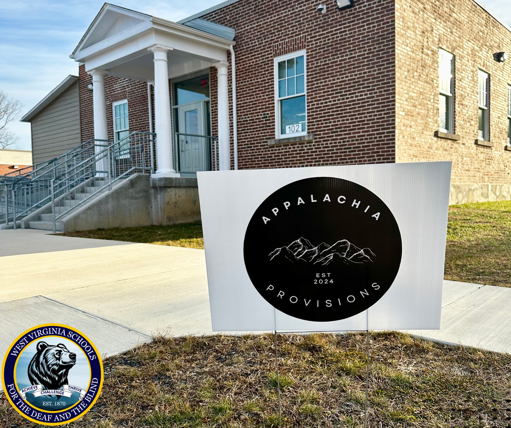 Exterior of the Appalachia Provisions Café on the WVSDB campus, with an Appalachia Provisions sign displayed in front of the brick building and the WVSDB logo in the lower left corner.