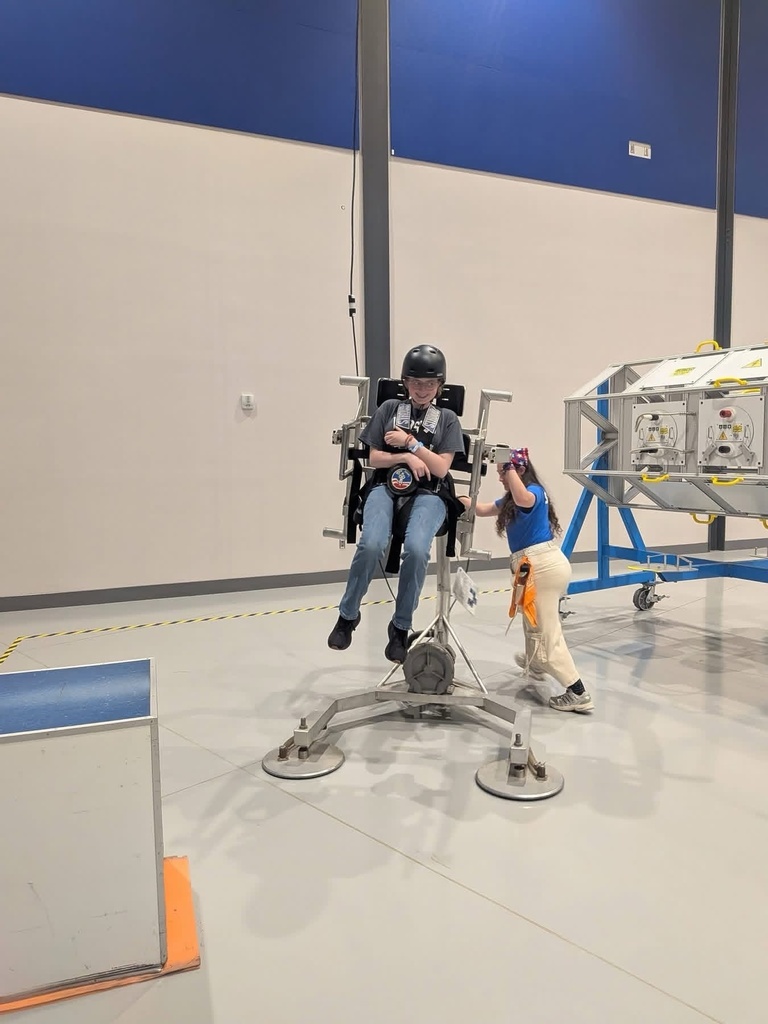 WVSDB student wearing a helmet and harness sits in a Space Camp simulator while an instructor assists nearby.