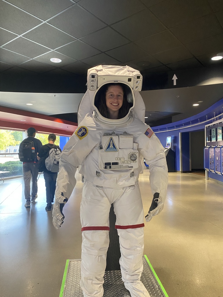 Smiling WVSDB teacher poses inside a full-size white astronaut suit during the Space Camp experience.