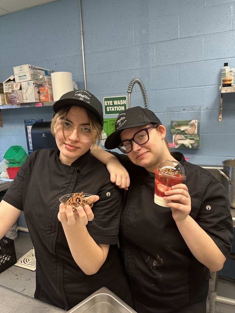 Two Appalachia Provisions culinary students smile for the camera while holding freshly prepared yogurt parfaits.