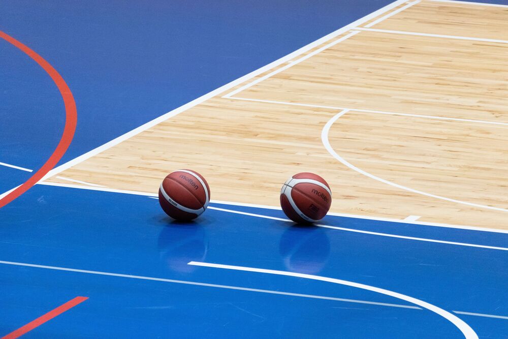 Photo of an indoor basketball court with 2 basketballs sitting on the floor
