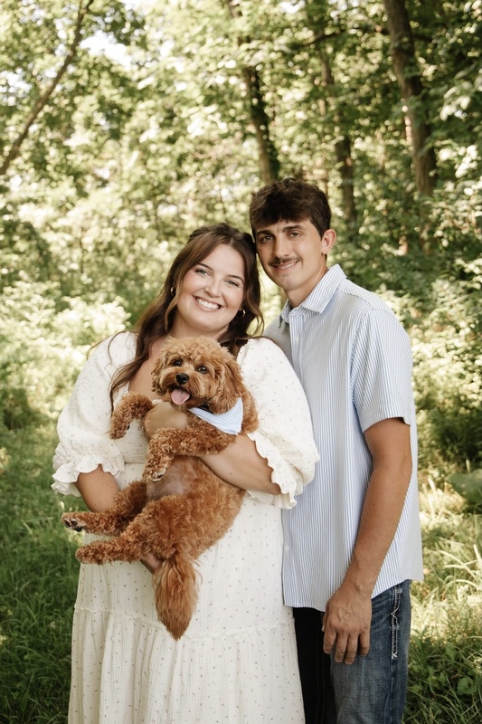 Image of two adults posing with a dog