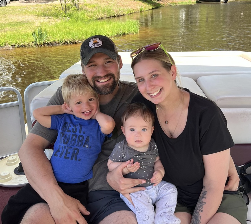 Image of two adults and two children in a boat on the river
