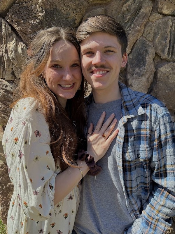 Image of two people posing in font of a rock wall