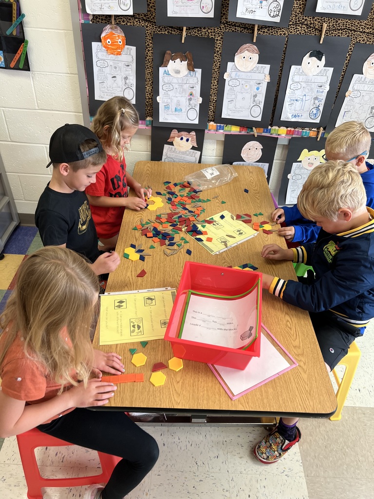 Students using pattern blocks at classroom table.