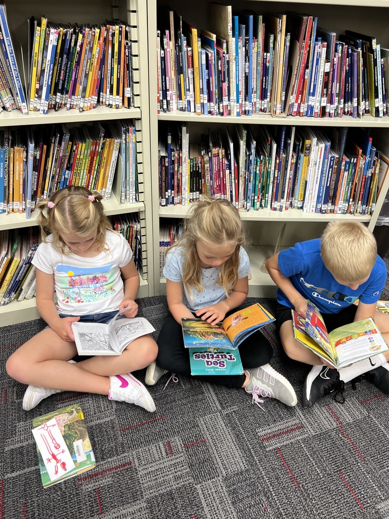 Students sitting on floor reading books in library.