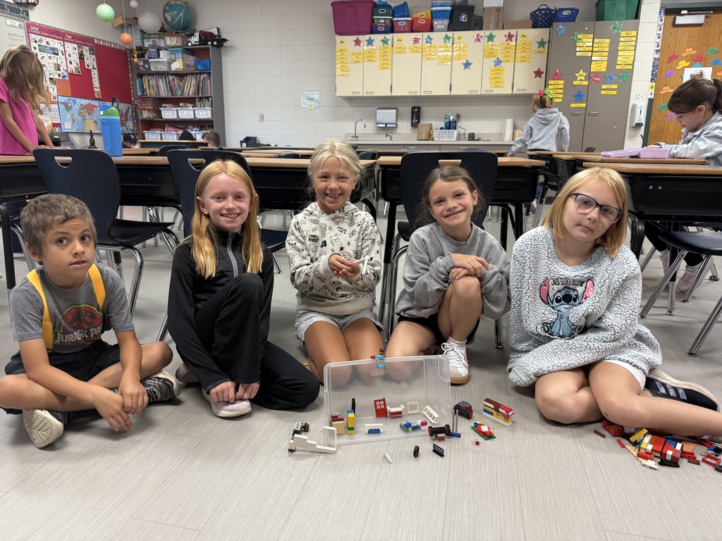 Group of five students sitting with their LEGO build and smiling for the camera.