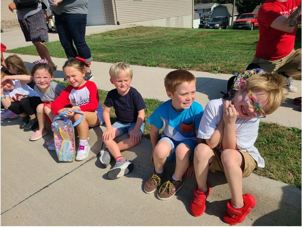 Students sitting in on the sidewalk preparing to watch the homecoming parade.