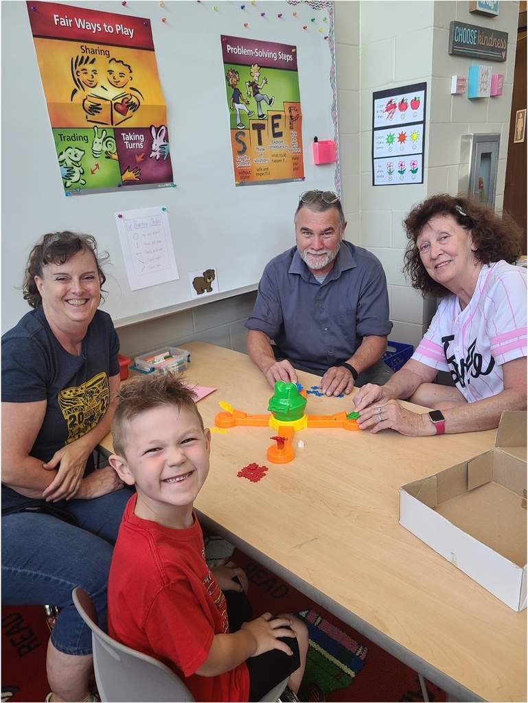 A student sitting at a table playing a game with three adults.