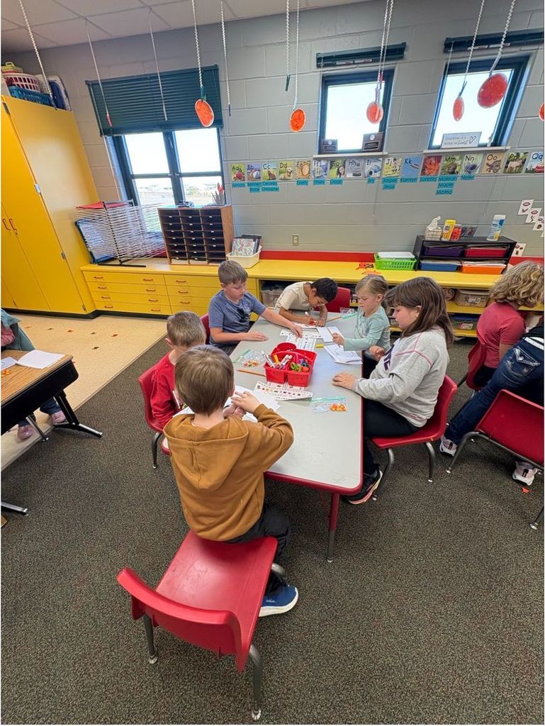 A group of students sits around a classroom table completing a candy corn math or writing activity.