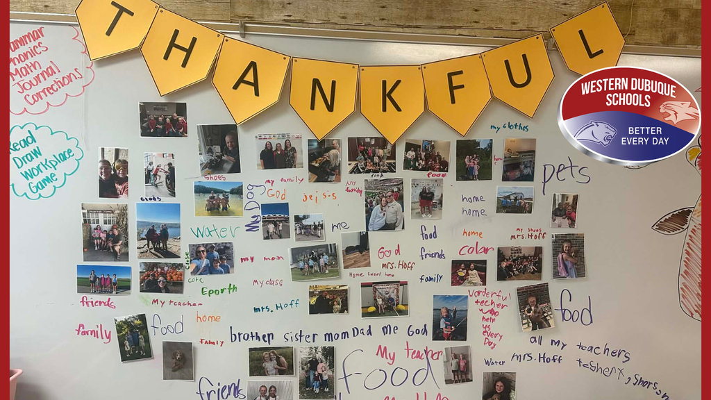 A classroom “Thankful” wall display featuring a banner spelling THANKFUL across the top. The whiteboard is covered with student photos and handwritten words of gratitude, including “family,” “food,” “pets,” “my teacher,” and “friends.” The Western Dubuque Schools logo appears in the upper right corner.