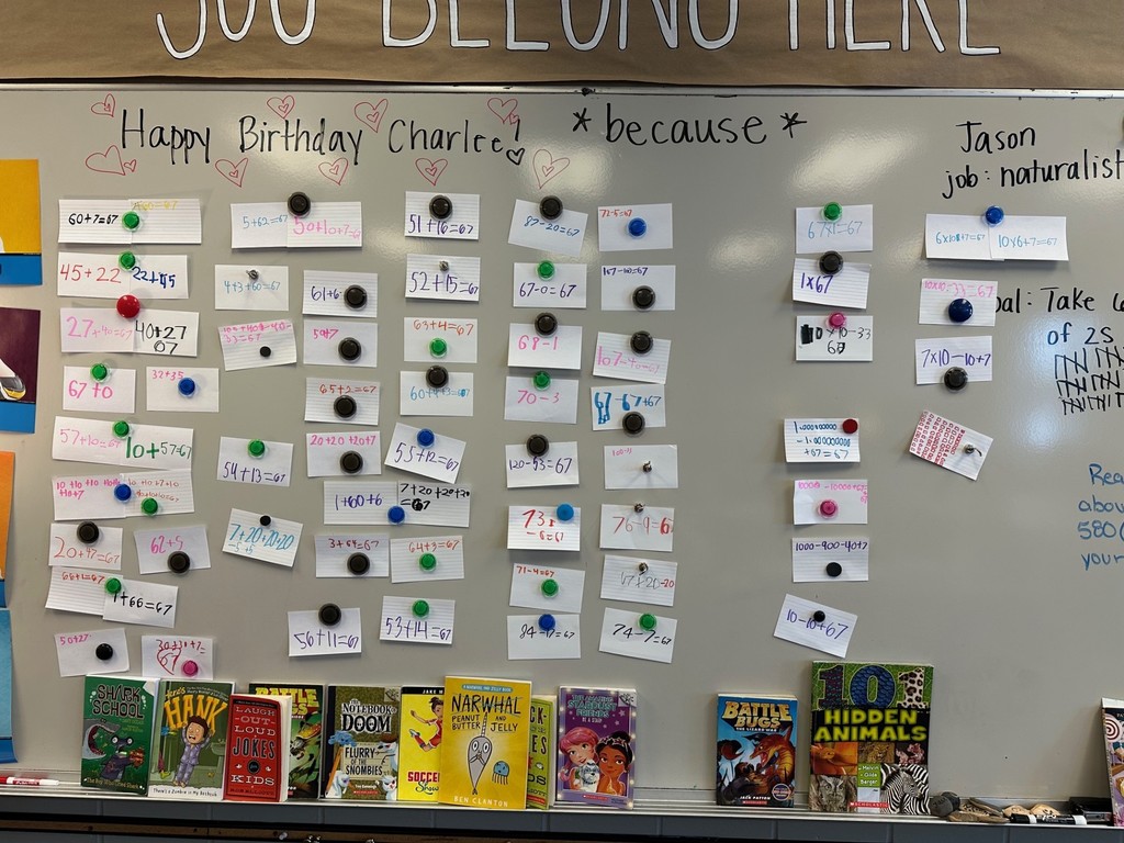 A classroom whiteboard filled with handwritten math problems displayed on small cards, each attached with colorful magnets.