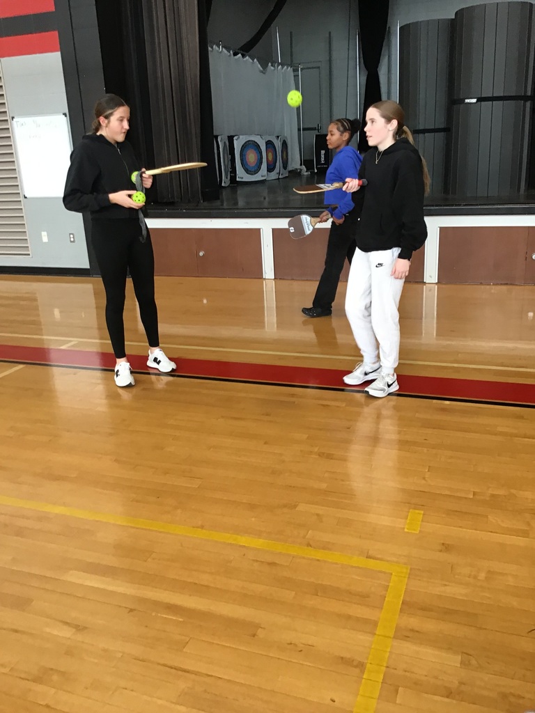 The students are learning pickleball in PE class