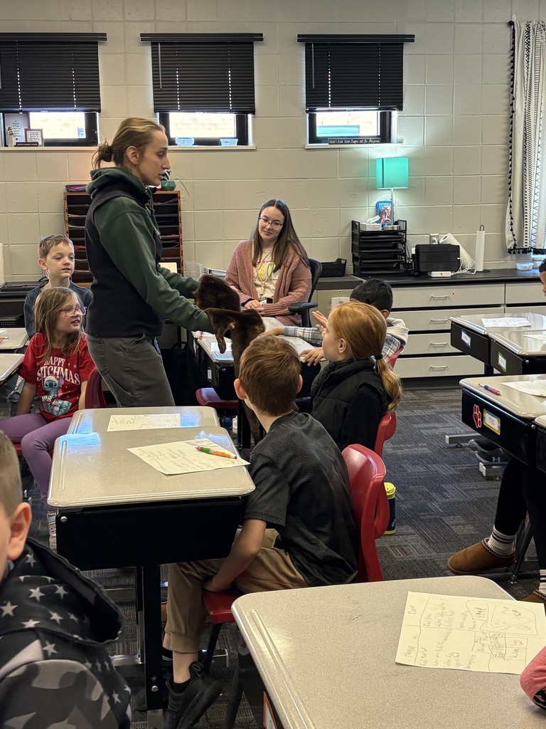 A classroom presenter shows students an animal pelt while they listen attentively at their desks.