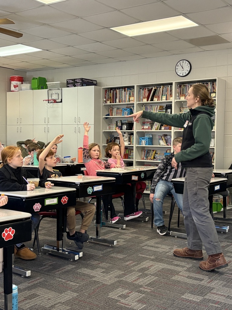 A presenter points to students with raised hands during an interactive classroom lesson.