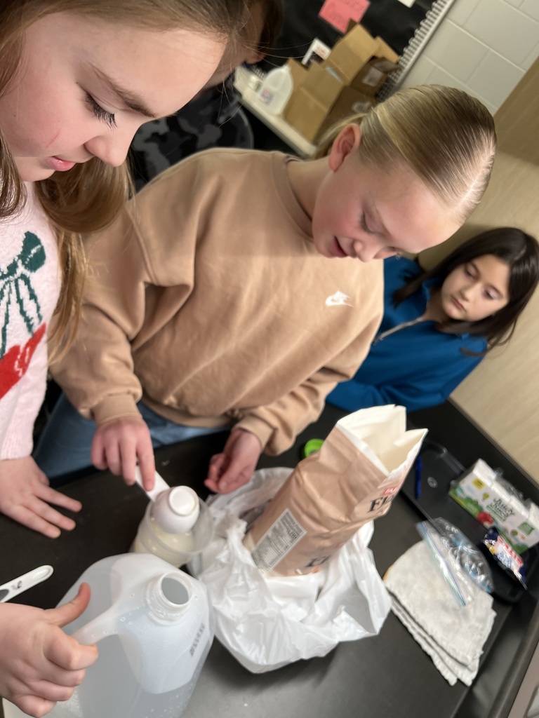 Students scoop and pour ingredients into a container during a hands-on activity.