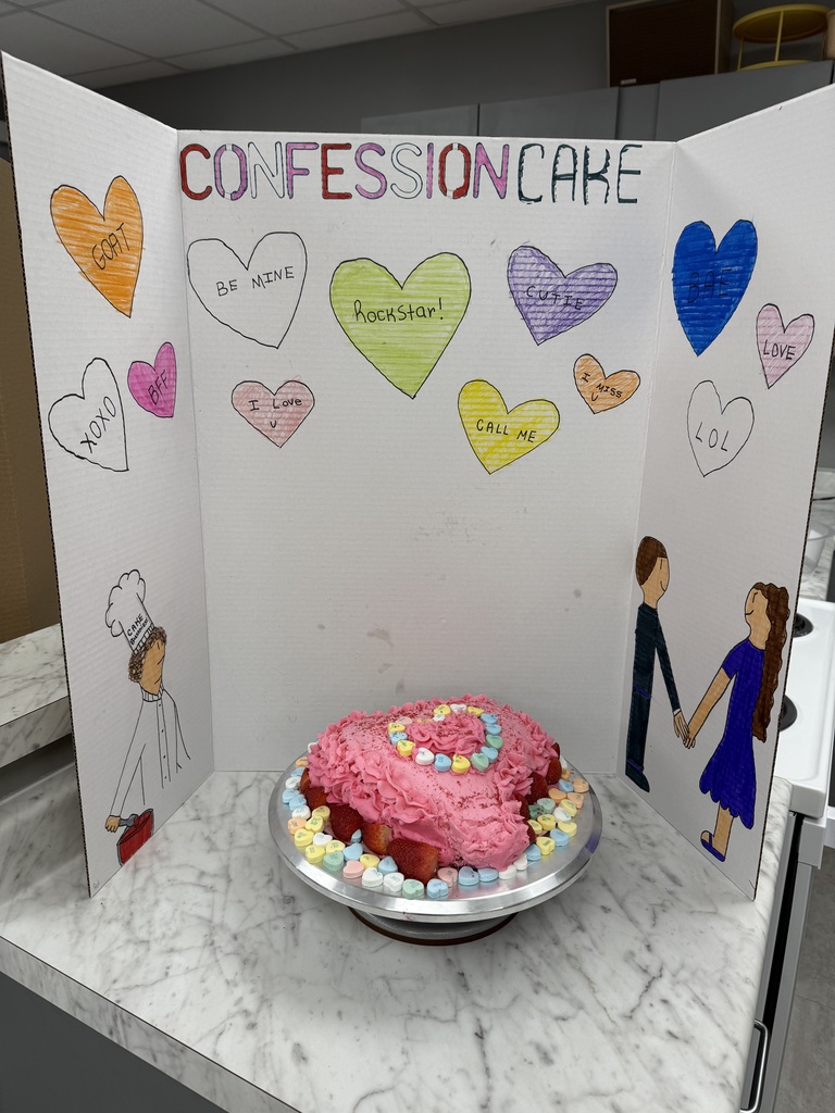 Heart-shaped “Confession Cake” surrounded by conversation heart candies and a hand-drawn themed backdrop.